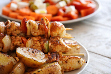Chicken skewers close-up with vegetables and roasted potatoes.

