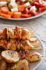 Chicken skewers close-up with vegetables and roasted potatoes.

