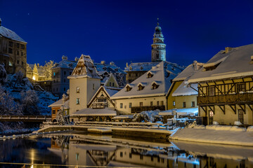 Obraz premium Winter view of Cesky Krumlov, picturesque houses under the castle with snow-covered roofs. Narrow streets and the Vltava river. Travel and Holiday. Christmas time. UNESCO World Heritage. Czechia