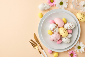 Easter table setting: a feast for the eyes. Top view shot of a white plate filled with pastel-colored eggs, cutlery, fresh white and pink flowers on beige background with space for text or ads