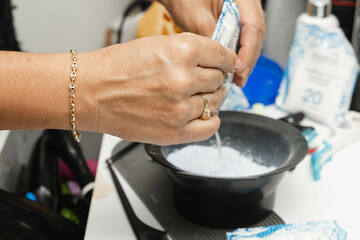 Stylist preparing hair dye for her client in her beauty salon. Hairdresser and cosmetics. Bleaching.