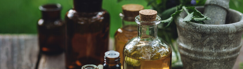 Natural organic essential oil in small glass bottles on wooden background. Homemade production for spa, sauna, bath. Relaxation, alternative medicine, remedy, naturopathy, pure ingredients