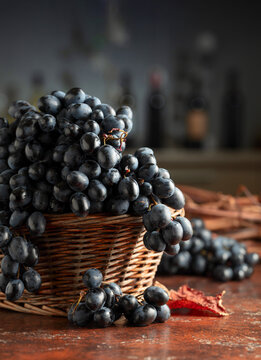 Blue grapes in old basket on a brown vintage table.