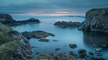 Obraz premium A tranquil lake nestled among rocky headlands and lush grass, with a vibrant sky above and a peaceful bight stretching out towards the horizon