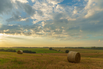 A haystack in a field against the background of beautiful clouds after the rain. Harvesting of...