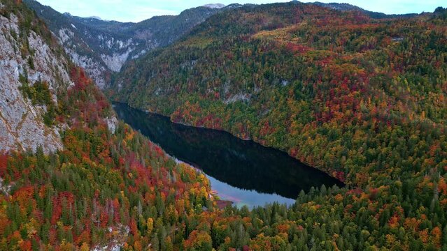 Lake Toplitz in mountain valley with colorful autumn forest all around.