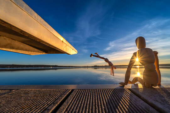 Lustiges Foto von zwei Holzfiguren beim Baden am See im Sonnenuntergang