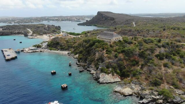 Tugboat beach in curacao with clear waters and rugged coastline, aerial view