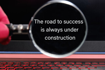 The road to success is always under construction text the phrase is written through a magnifying...