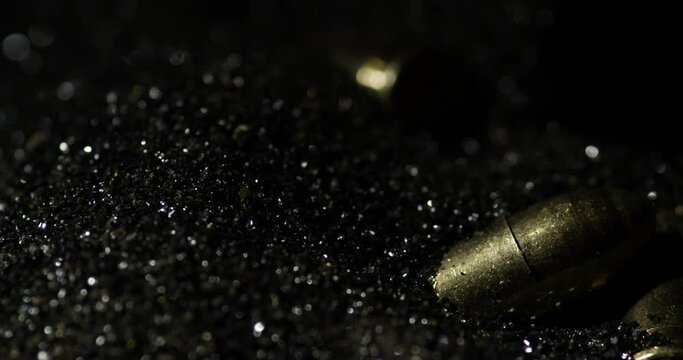 9&times;19mm Parabellum bullets macro detail closeup shot fall on gunpowder, slowmo
