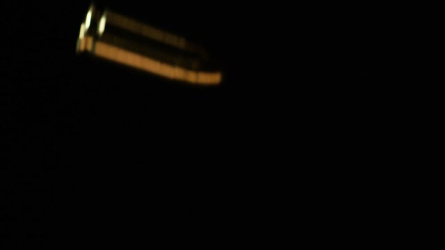 9mm Parabellum Bullets Falling Against Black Background. Slow Motion Shot