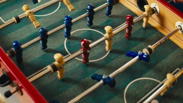 Close-up of a foosball table game with red and blue players and a white ball in motion