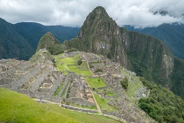 Papier peint Machu Picchu View of the ancient mountains of Machu Picchu and part of the city ruins, under a cloudy sky