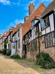 Old timbered and brick houses lined with flowers on charming cobblestone street