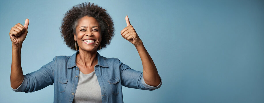 Beautiful elderly lady afro American happy with your thumbs on; isolated on blue background and space for the text.