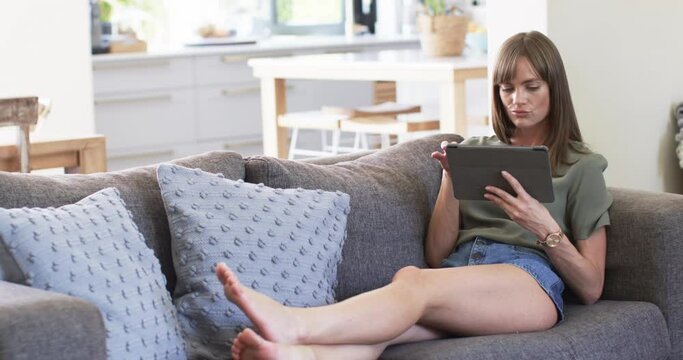 Middle-aged Caucasian woman relaxes on a sofa at home, with copy space
