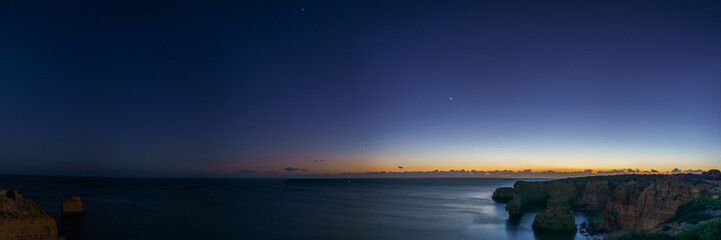 Panorama of cliffs at the coast of Atlantic Ocean during dusk with planets Venus, Saturn and...