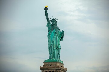 Fototapeta premium Iconic Statue of Liberty standing against a cloudy sky