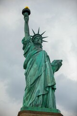 Fototapeta premium Low-angle view of the iconic Statue of Liberty standing against a cloudy sky