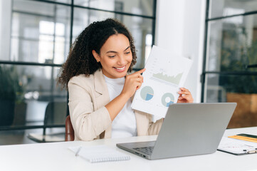 Successful positive multiethnic curly haired businesswoman, financial top manager, working on a...