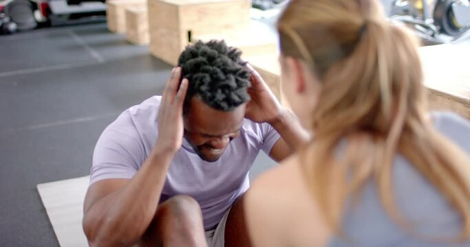 Fit African American man exercising at the gym with a trainer