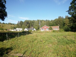 Rural structures on a grassy green field surrounded by trees