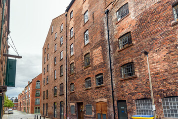 Fototapeta premium Old brick building converted in lofts along a narrow cobbled street in a redevelopment on a cloudy summer day