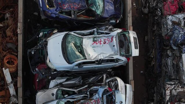 Aerial drone image captures a view of an automobile junkyard featuring compressed sedans.