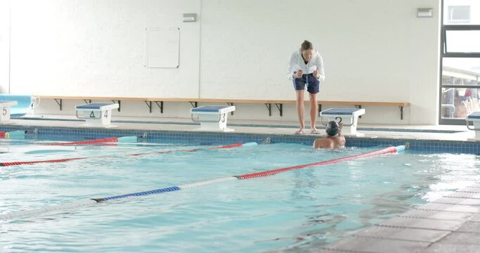 Swimming coach giving instructions at the poolside, with copy space