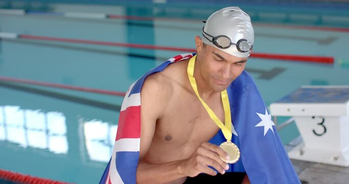 Proud swimmer displays his gold medal at the pool with the Australian flag