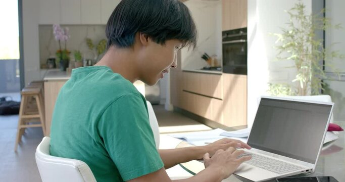 Teenage Asian boy focused on his laptop at home