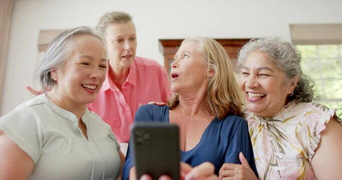 Senior diverse group of women laughing and looking at a smartphone