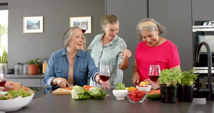 Caucasian woman, Asian woman, and senior biracial woman enjoy a home cooking session preparing a mea