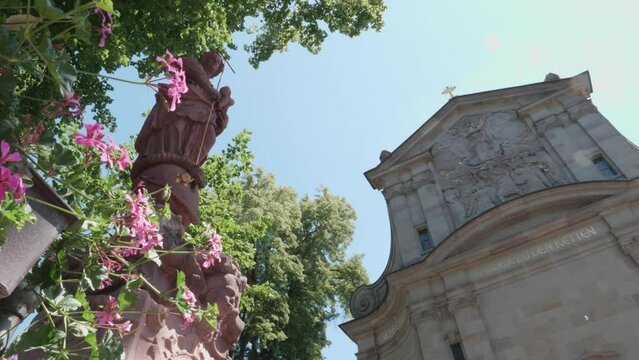 View of the Maria zu den Ketten church in Zell am Harmersbach on a summer's day, statue of the Virgin Mary in the foreground