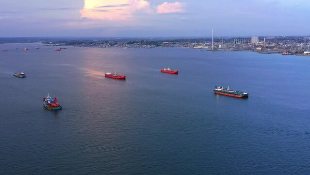 Panning Aerial view of Oil Tankers and Pertamina oil refinery in the background during sunset - Port of Balikpapan - East Kalimantan, Indonesia