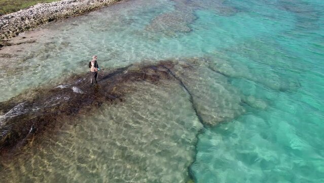 Aerial view Man fly fishing looking for parrot fish underwater shallow saltwater, caribbean sea