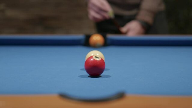 A man chalks his cue and then pots a red ball