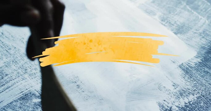 Animation of yellow paint smudge with copy space over hand with paint brushing background
