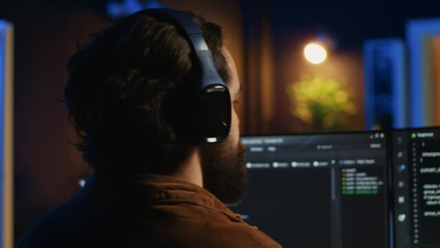 Technician putting headphones on while using coding to fortify firewalls, teleworking for IT company. Computer scientist listening music and upgrading binary code scripts in home office, camera A