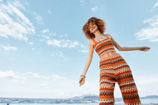 Illuminate the Freedom: Smiling Hippie Woman Dancing on Beach, Embracing Nature's Beauty.