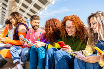 Diverse young LGBT friends using smartphone together outdoors. Communication and LGBTI community concept.