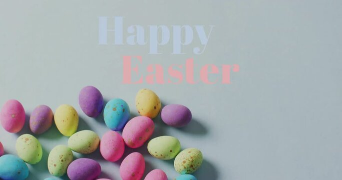 Animation of happy easter text over colourful easter eggs on grey background