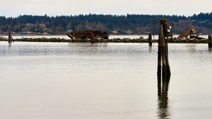 Dusk, high tide,  view of two of the rusty old navy hulls that were formerly part of a breakwater