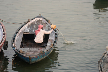 Obraz premium Varanasi, Uttar Pradesh / India - May 7, 2015 : The sailor is draining water out of the boat at Varanasi ghat.