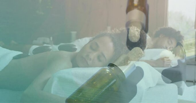 Animation of essential oil bottles over diverse couple having hot stones massage