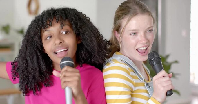 Animation of white lights over happy diverse teenage girls with microphones singing karaoke at home