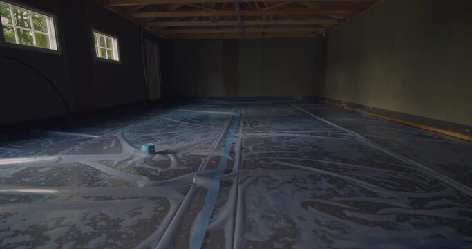 Fresh concrete floor drying with natural light in a spacious garage, sunlight from windows