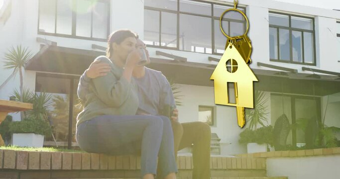 Animation of gold house key and key fob over happy biracial couple by house