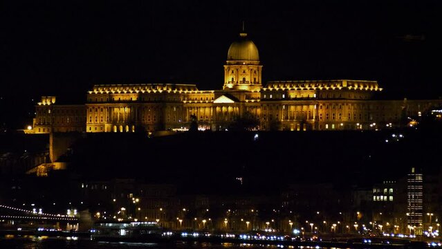 Budapest city (Hungary capital) center view with illuminated Buda Castle and Danube river at night, gothic architecture, light reflections, distant wide shot