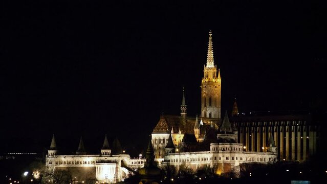 Budapest city (Hungary capital) center view and Danube river at night, gothic architecture, light reflections, illuminated church tower, distant medium shot
